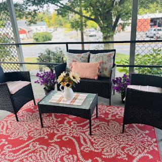 A cozy outdoor seating area decorated with comfortable chairs, a charming table, and vibrant flowers.