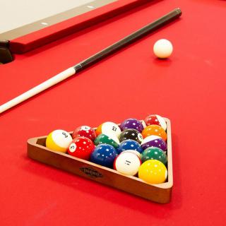 A pool table with a set of billiard balls arranged in a triangle, ready for a game.