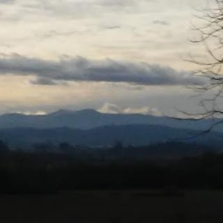 A serene view of the mountains under a cloudy sky during dusk.