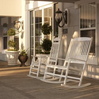 Two white rocking chairs on a sunlit porch with potted plants.