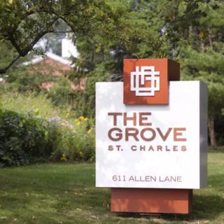 A sign for The Grove in St. Charles, set amidst a landscaped area with trees.