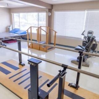 A physical therapy room equipped with parallel bars and exercise machines for rehabilitation.