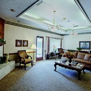 A spacious living room with elegant furnishings and decor, featuring a sofa set, coffee table, and chandelier.