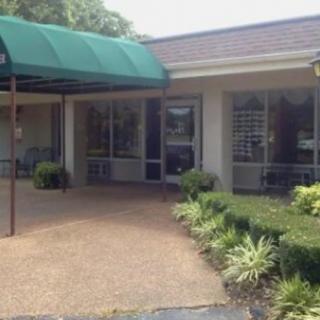 A building entrance with a green awning and surrounding greenery.