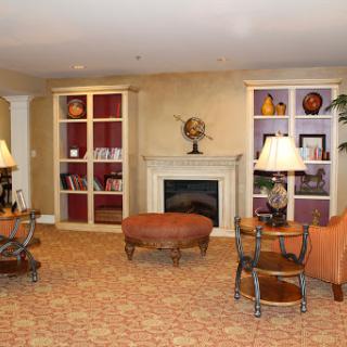 A cozy living room featuring a fireplace, comfortable seating, and decorative shelves.