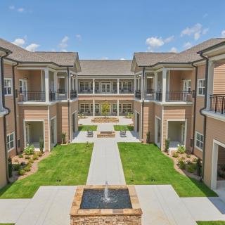 A modern apartment complex with a landscaped courtyard and central fountain.