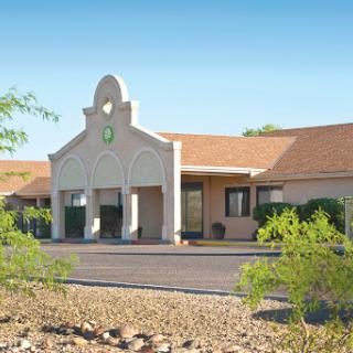 A commercial building with desert landscaping under a clear blue sky.
