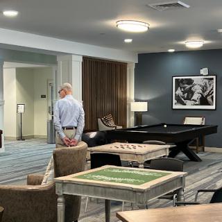 A man stands in a modern lounge area featuring a pool table and comfortable seating.