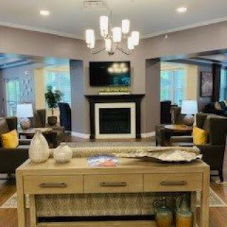 A modern living room with a stylish chandelier, comfortable seating, and a fireplace beneath a wall-mounted TV.