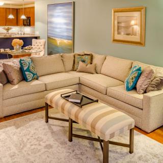 A cozy living room with a beige sectional sofa, colorful pillows, and modern decor.