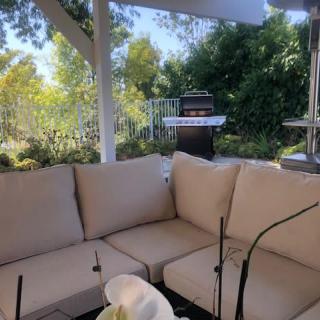 A cozy outdoor patio with comfortable seating and a grill in the background.
