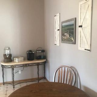 A cozy kitchen corner with a wooden table and chair, featuring rustic decor on the walls.