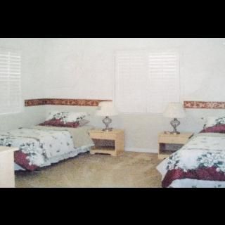 A cozy bedroom featuring twin beds with floral bedding and matching nightstands.