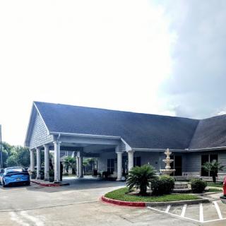 A welcoming entrance to a well-maintained building, featuring a landscaped area and a parked car.