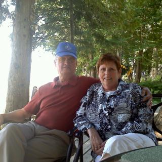 A couple sitting together outdoors, enjoying a relaxing day in a wooded area.