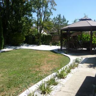 A tranquil backyard with a gazebo overlooking a spacious lawn and surrounding trees.