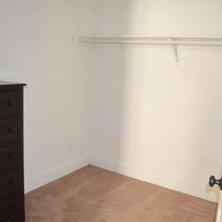 An empty closet with a dresser and a single shelf.