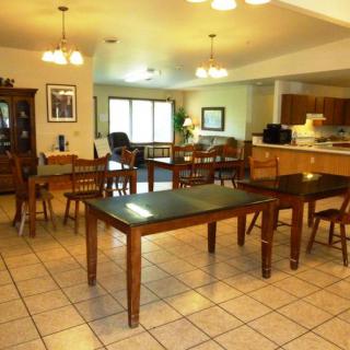 An open-plan living and dining area with wooden tables and chairs, adjacent to a kitchen.