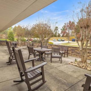 A peaceful outdoor patio area with chairs and tables surrounded by trees.