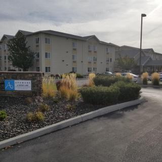 A residential apartment complex with well-maintained landscaping and a parking area on an overcast day.