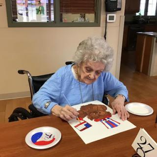 An elderly woman engaged in a creative painting activity, showcasing her artistic skills.