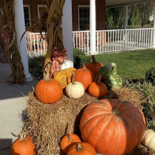 A seasonal display of pumpkins and hay bales on a porch, celebrating the autumn season.
