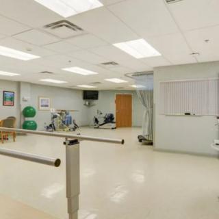 A well-equipped physical therapy room with exercise machines and parallel bars.