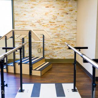 A physical therapy room equipped with parallel bars and steps for rehabilitation exercises.