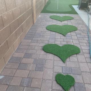 A decorative stone pathway with heart-shaped patches of artificial grass.