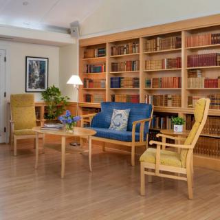 A cozy reading area with wooden furniture and a wall of bookshelves.