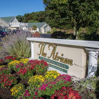 A landscaped garden with colorful flowers surrounds a sign reading 'The Atrium' near a building.
