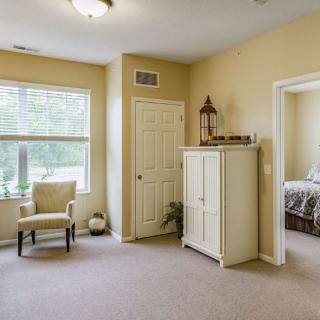 A minimalist bedroom interior with a wardrobe, chair, and window allowing natural light.