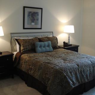A cozy bedroom with a neatly made bed flanked by two nightstands and lamps.
