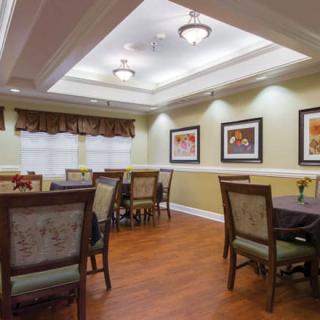 A well-lit dining room with multiple tables and chairs, featuring artwork on the walls.