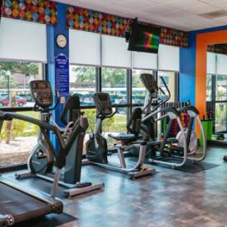A gym with various exercise machines, including treadmills, stationary bikes, and elliptical trainers.