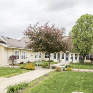 A single-story house surrounded by a well-maintained lawn and garden with trees.
