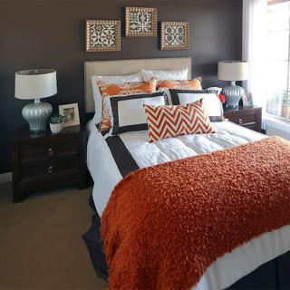 A modern bedroom with stylish bedding and warm accents.