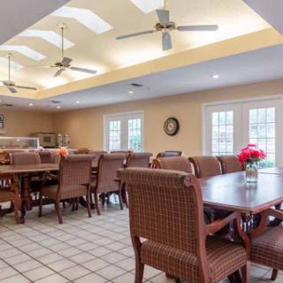 A spacious and inviting dining area featuring wooden tables, comfortable chairs, and ceiling fans for a relaxed atmosphere.