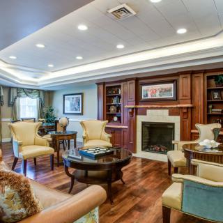 A cozy and elegantly designed living room featuring a fireplace, comfortable seating, and wooden bookshelves.