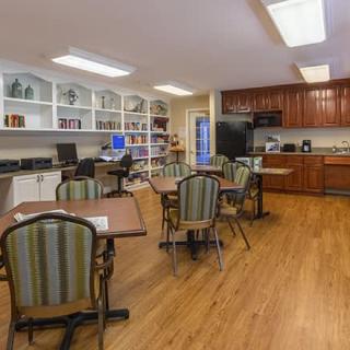 A cozy kitchen and dining area with tables, chairs, cabinets, and bookshelves.