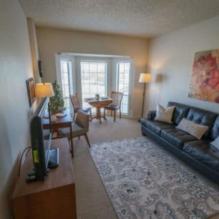A cozy living room with a sofa, TV, and a dining set near large windows.
