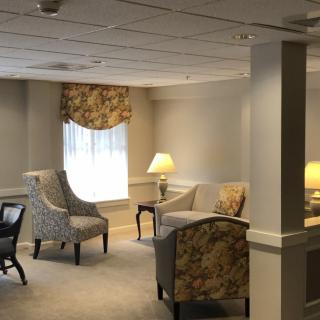 A cozy living room interior with chairs, lamps, and a window.