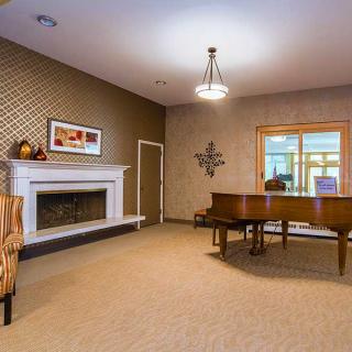 A cozy living room featuring a grand piano and a fireplace.