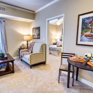 A cozy apartment living room featuring a sofa, table with place settings, and decorative artwork.