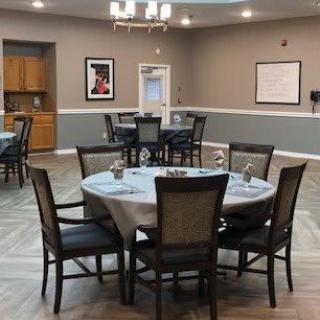A neatly arranged dining area with round tables and chairs, set for an elegant meal.