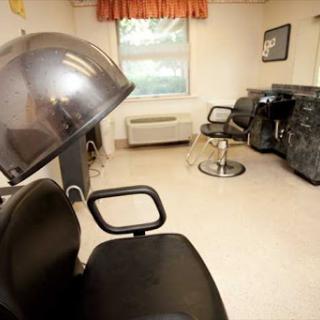 A spacious and well-lit hair salon with styling chairs and a drying station.