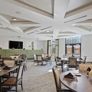 A modern dining hall with neatly arranged tables and chairs, featuring contemporary design elements.