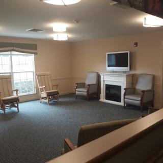 A spacious living room with seating, a fireplace, and a television.