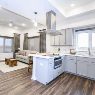 A modern open-concept kitchen and living room with stylish white cabinets and hardwood floors.