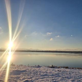 A serene winter landscape at sunrise, with a beautiful reflection on the lake.